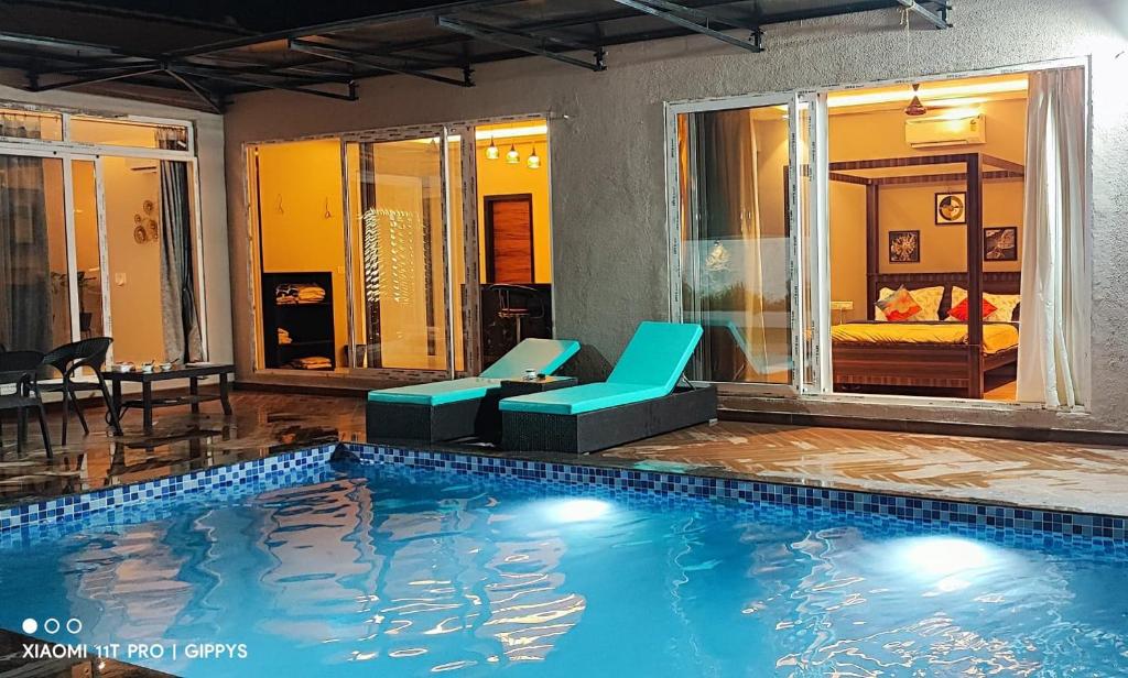 - une piscine avec deux chaises et un lit dans l'établissement Khopoli XoXo Villa, à Khopoli