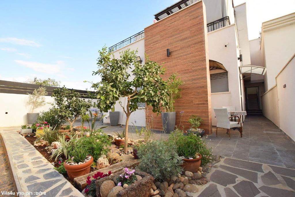 einen Garten mit Pflanzen und Bäumen vor einem Gebäude in der Unterkunft Allen suite in Migdal