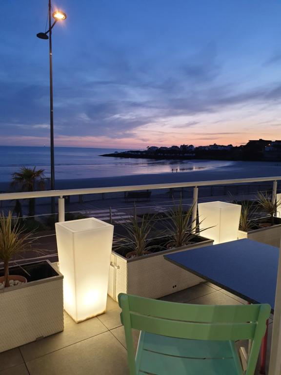 einen Tisch und Stühle auf einem Balkon mit Meerblick in der Unterkunft Hôtel The Originals Miramar, Royan Pontaillac in Royan