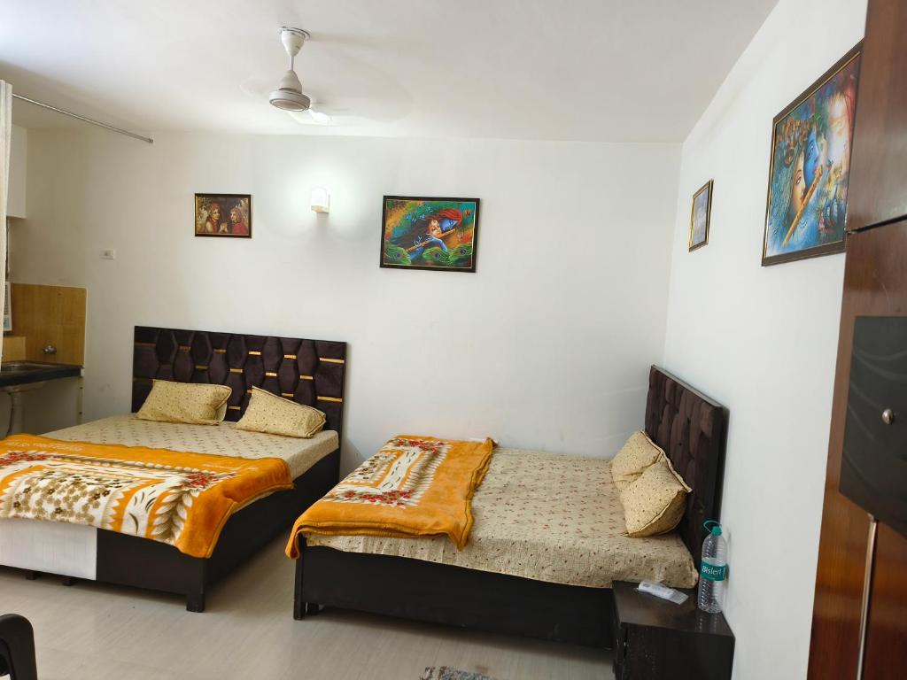2 camas en una habitación con paredes blancas en Omaxe eternity, en Vrindāvan