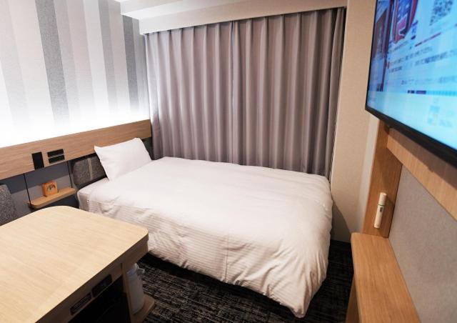 a hotel room with two beds and a flat screen tv at R&B Hotel Ueno Hirokoji in Tokyo