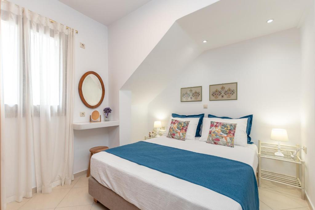 a white bedroom with a blue and white bed and a window at Amaranto Naxos 2 in Naxos Chora
