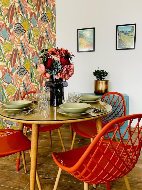 a table with chairs and a vase of flowers at L’escale 175 in Divatte sur Loire