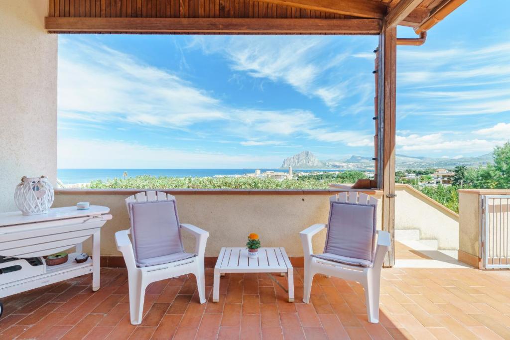 Duas cadeiras e uma mesa num pátio com vista para o oceano em Villa La Pineta al Mare em Erice
