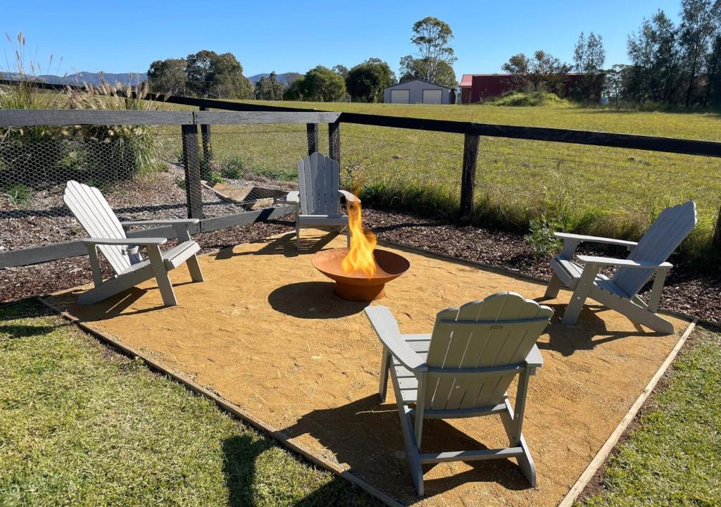 een vuurplaats met twee stoelen en een brandkraan bij Coolalta Cottage - Hunter Valley in Nulkaba