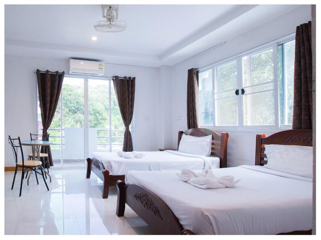 1 dormitorio con 3 camas, mesa y ventana en Namhasin House, en Ko Tao