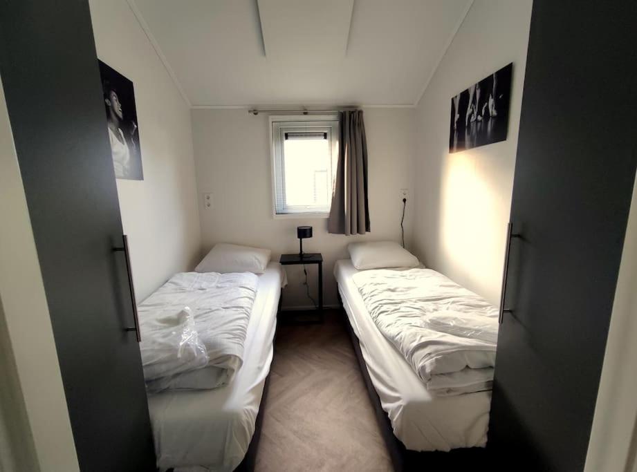twee bedden in een kleine kamer met een raam bij Traumhaftes Chalet am Veluwemeer, Bad Hoophuizen in Hulshorst