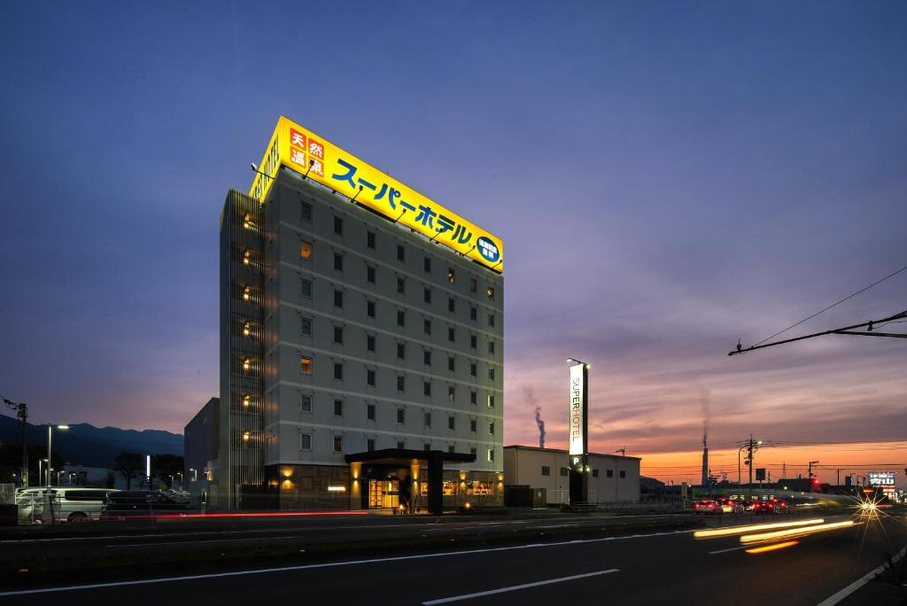 a hotel building with a sign on top of it at Super Hotel Shikoku-chuo in Shikokuchuo