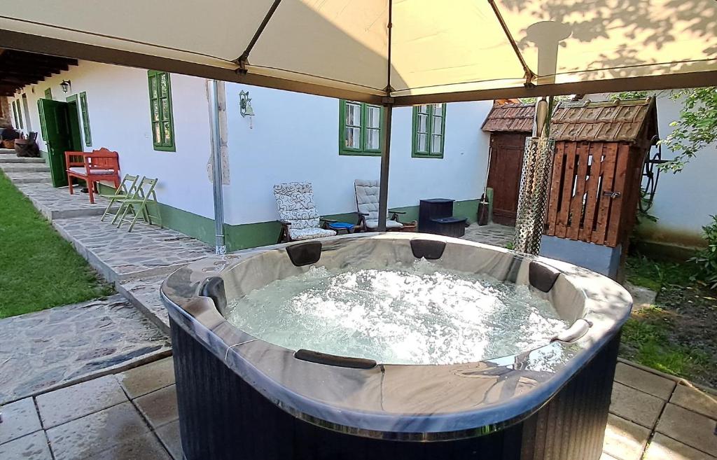 a hot tub in a yard with an umbrella at Padláskincsek Vendégház in Nagybörzsöny