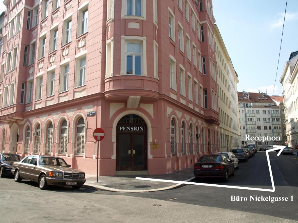a pink building with cars parked in front of it at Hotel Liechtenstein Apartments II in Vienna