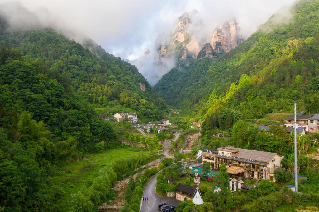 a village in a valley with mountains in the background at Homeward Mountain Resort in Zhangjiajie