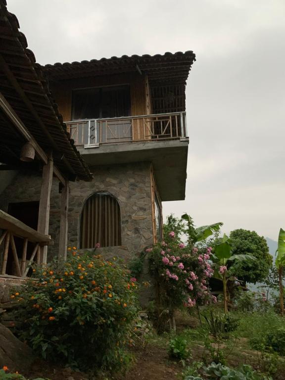 um edifício com varanda e algumas flores em Homstay Gốc Vải em Dan Mey