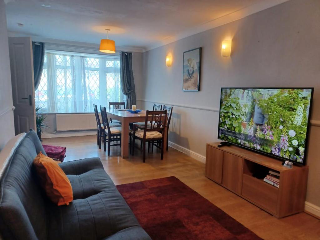 ein Wohnzimmer mit einem Sofa und einem Flachbild-TV in der Unterkunft Melo House Grove-Huku Kwetu Spacious - Luton & Dunstable -4 Bedroom-L&D Hospital - Suitable & Affordable Group Accommodation - Business Travellers in Houghton Regis