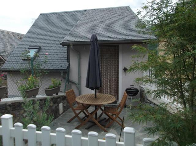 une table et des chaises avec un parasol sur une terrasse dans l'établissement Gite appartement location vacance montagne pyrenees, à Soulom