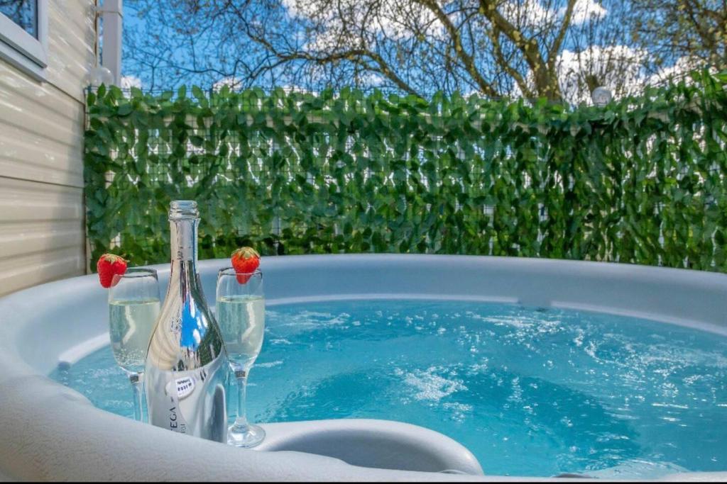 a hot tub with two bottles and glasses in it at Tattershall Lakes Private Hot Tub Lodge - sleeps 6 in Lincoln