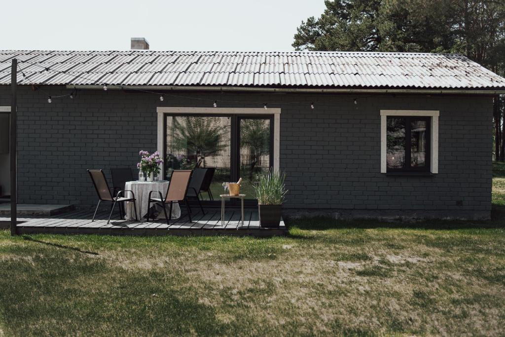 uma casa com uma mesa e cadeiras num pátio em Under The Pine em Engure