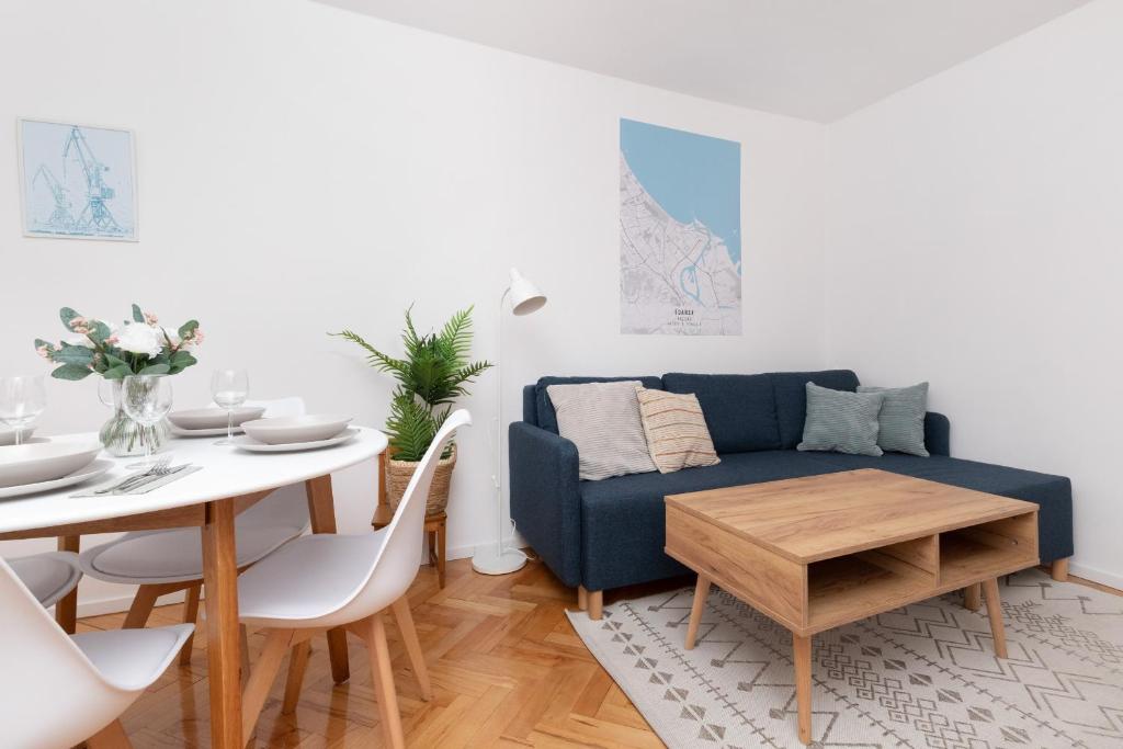ein Wohnzimmer mit einem blauen Sofa und einem Tisch in der Unterkunft Cosy Apartment for 5 Guests Gdańsk Wrzeszcz by Renters in Danzig