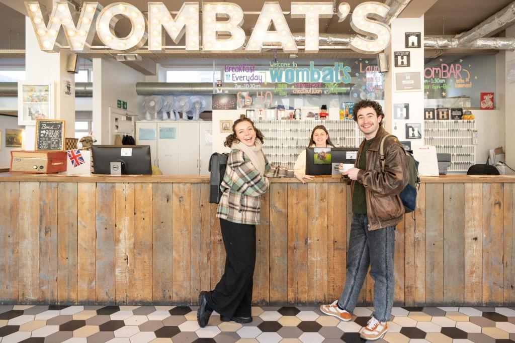 a man and a woman standing at a counter at Wombat's City Hostel London in London