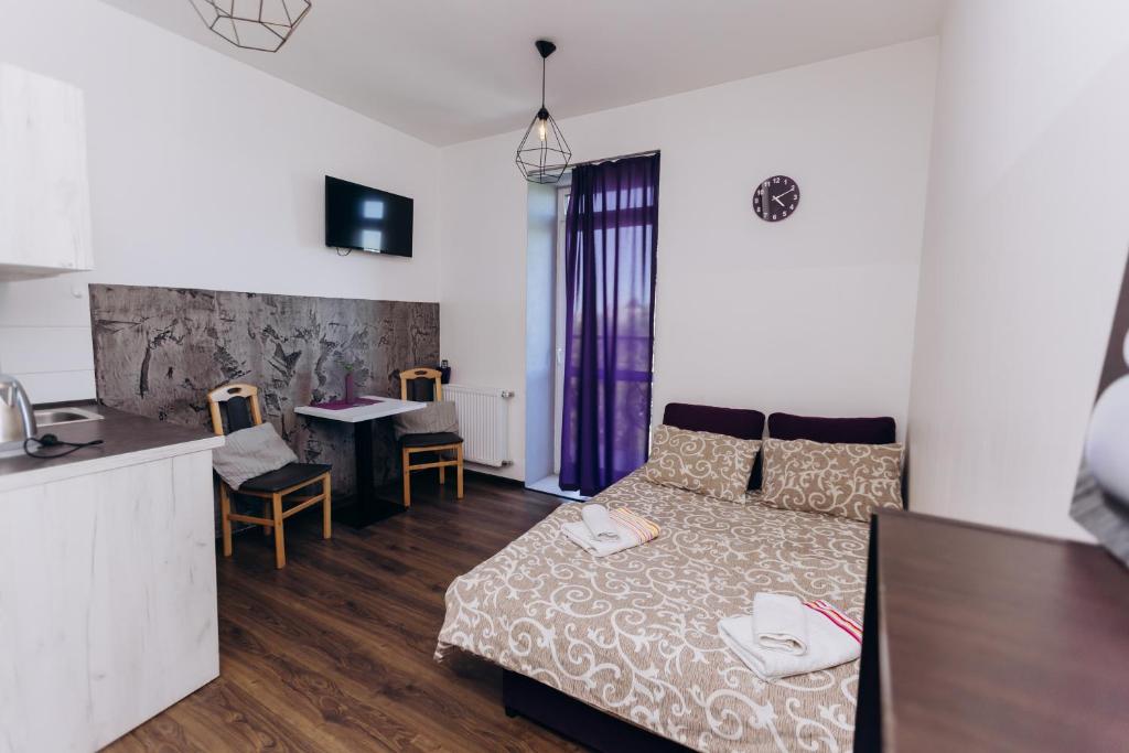 a bedroom with a bed and a kitchen with a table at Нові Apartments біля ЖД вокзалу in Ivano-Frankivsʼk