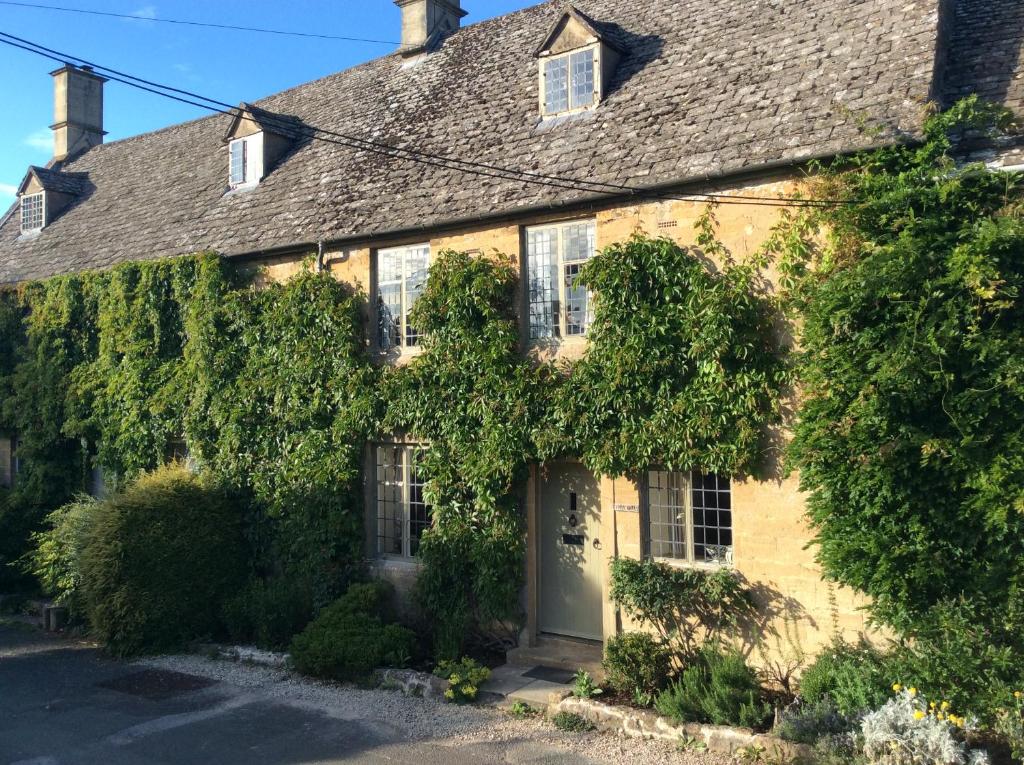 een met klimop overdekt huis met een witte deur bij Beautiful grade 2 listed cotswold Stone Cottage in Chipping Norton