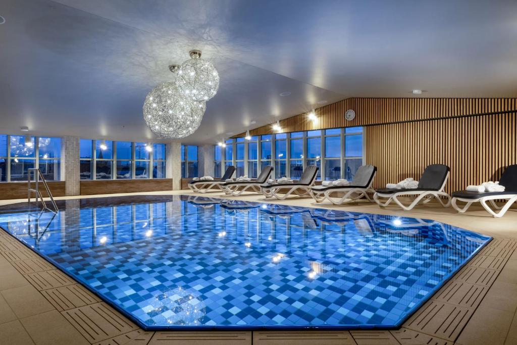 a large swimming pool with chairs and a chandelier at Maritim Hotel München in Munich