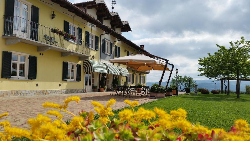 a yellow building with a patio and an umbrella at Agriturismo Cascina Rabalot in Diano dʼAlba