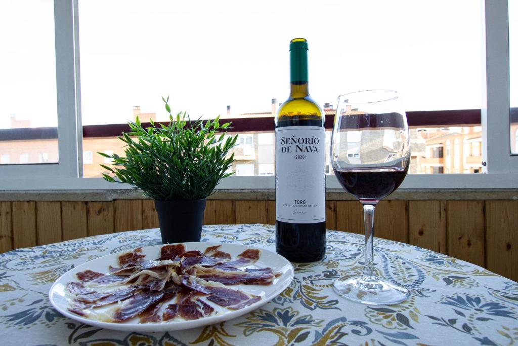 einen Tisch mit einem Teller Essen und einer Flasche Wein in der Unterkunft Acogedor piso de 6 camas in Salamanca