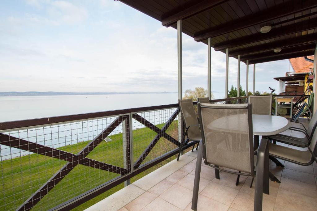 a balcony with a table and chairs overlooking the water at 299 - Teljes panorámás közvetlen balatonparti exkluzív apartman in Balatonőszöd