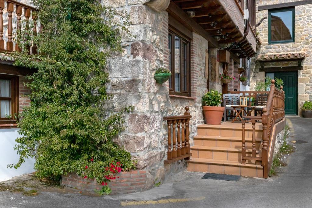 kamienny budynek z werandą ze stołem i drzewem w obiekcie CASA GERRA COMILLAS w mieście Comillas