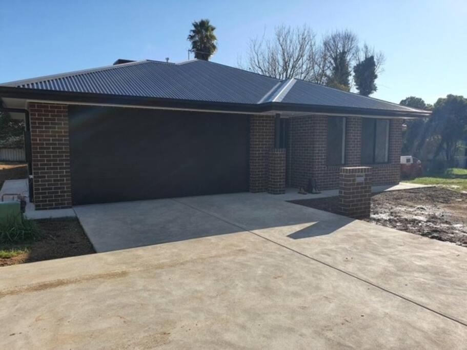 a garage with a black roof and a driveway at Killara Kottage in Tumut
