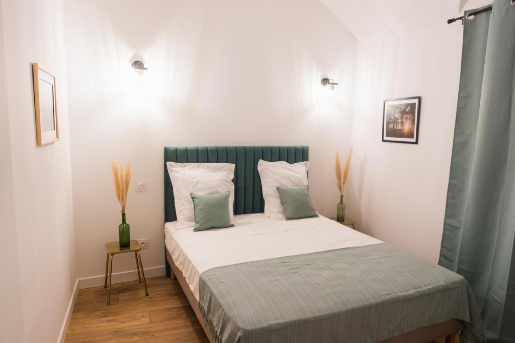 een slaapkamer met een groot bed met witte lakens en kussens bij Appartement cosy proche de la citadelle in Bastia