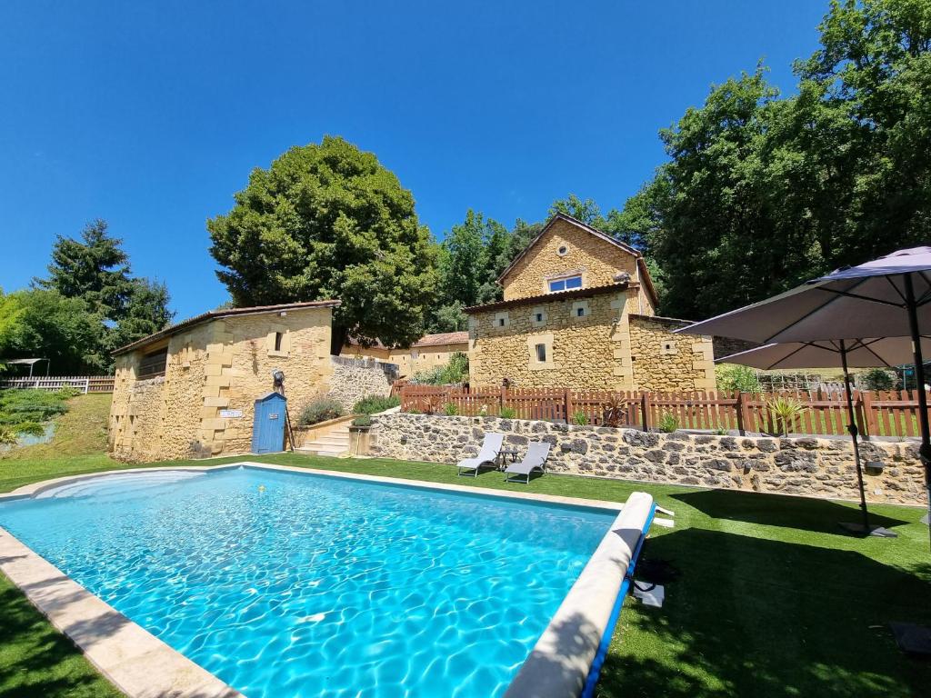 - une piscine en face d'un bâtiment en pierre dans l'établissement Le Clos de la Canéda, à Sarlat-la-Canéda