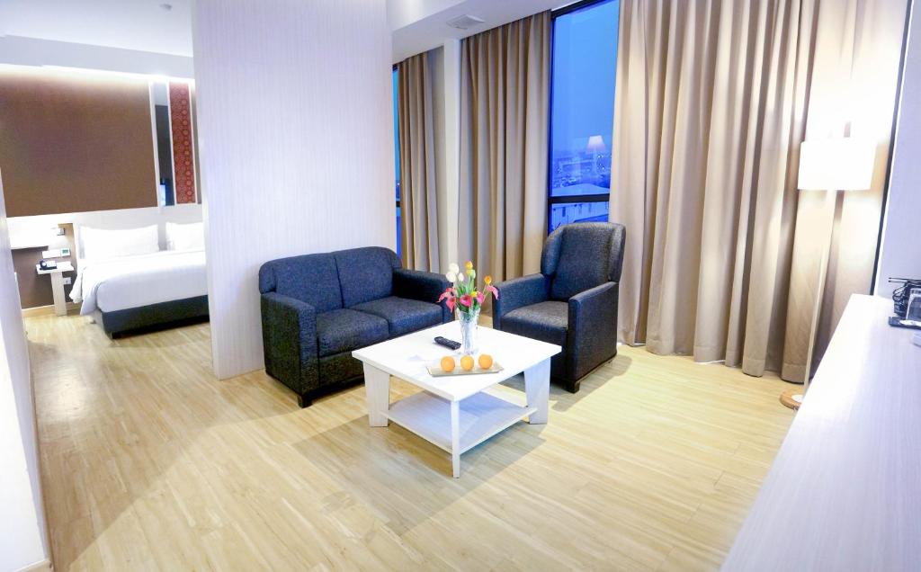 um quarto de hotel com duas cadeiras e uma mesa de centro em Harper Palembang by ASTON em Palimbão