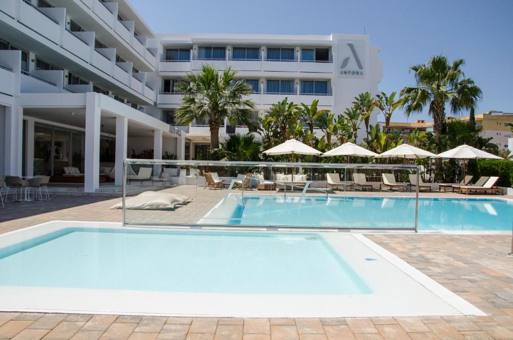 a swimming pool in front of a hotel at Hotel Anfora Ibiza in Es Cana