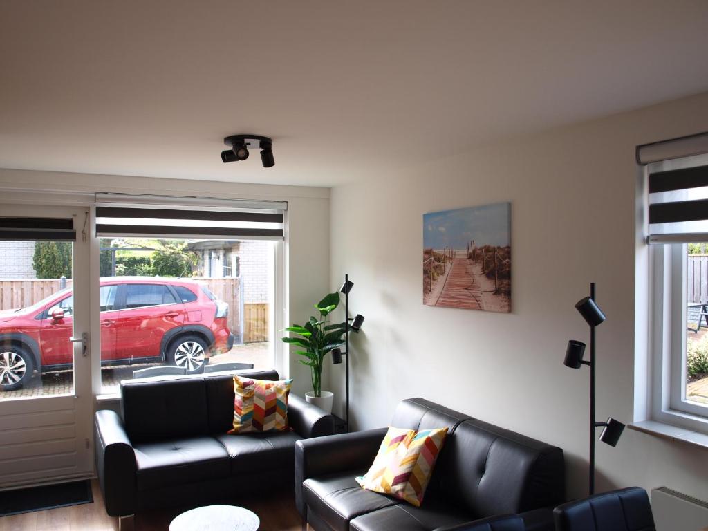 una sala de estar con 2 sofás negros y un coche rojo en Appartement ,Vakantiewoning, Koddelaan 29, en Zoutelande
