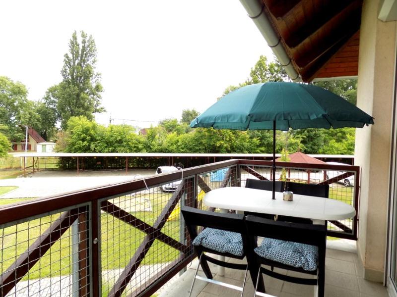 une table et des chaises avec un parasol sur un balcon dans l'établissement 58 - Hullám Üdülőparkban vízközeli modern stúdió apartman, à Balatonőszöd