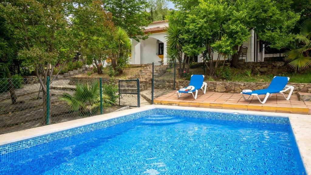 une piscine avec deux chaises bleues et une maison dans l'établissement Los Lirios Jimera de Libar by Ruralidays, à Jimera de Líbar