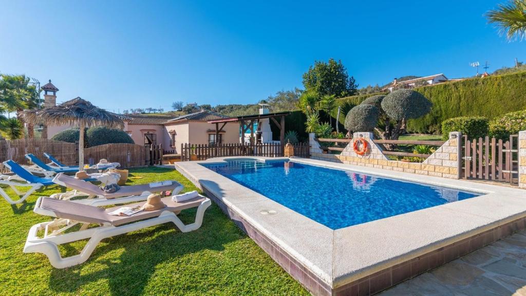 un patio trasero con piscina y tumbonas en Casa Rural la Higuera de Rios Antequera - La Higuera by Ruralidays, en Antequera