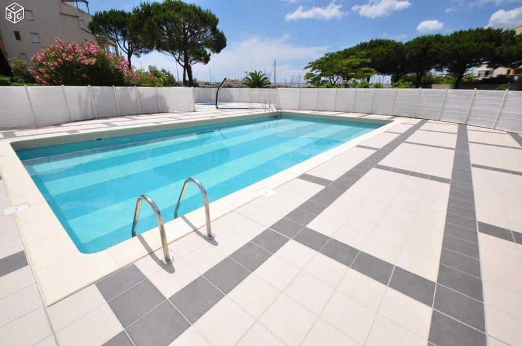 - une piscine avec du carrelage et une clôture dans l'établissement "Le Pharo" 17 Impasse du globe Appartement, au Cap d'Agde