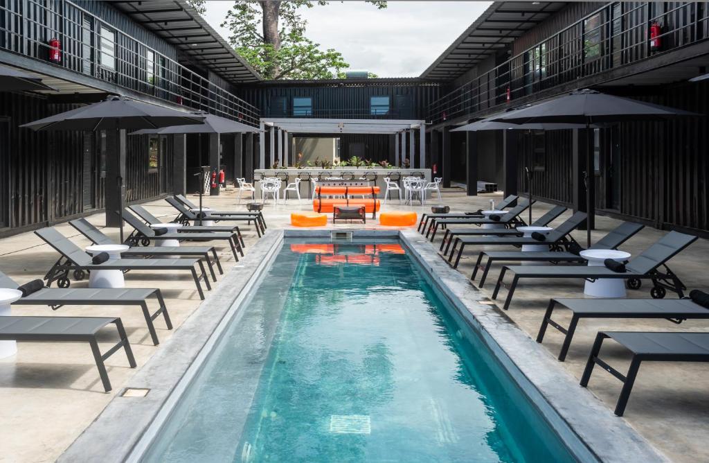 una piscina al aire libre con tumbonas, mesas y una mesa en Boxo Diani - Unique Beach Front Container Eco-Hotel en Diani Beach