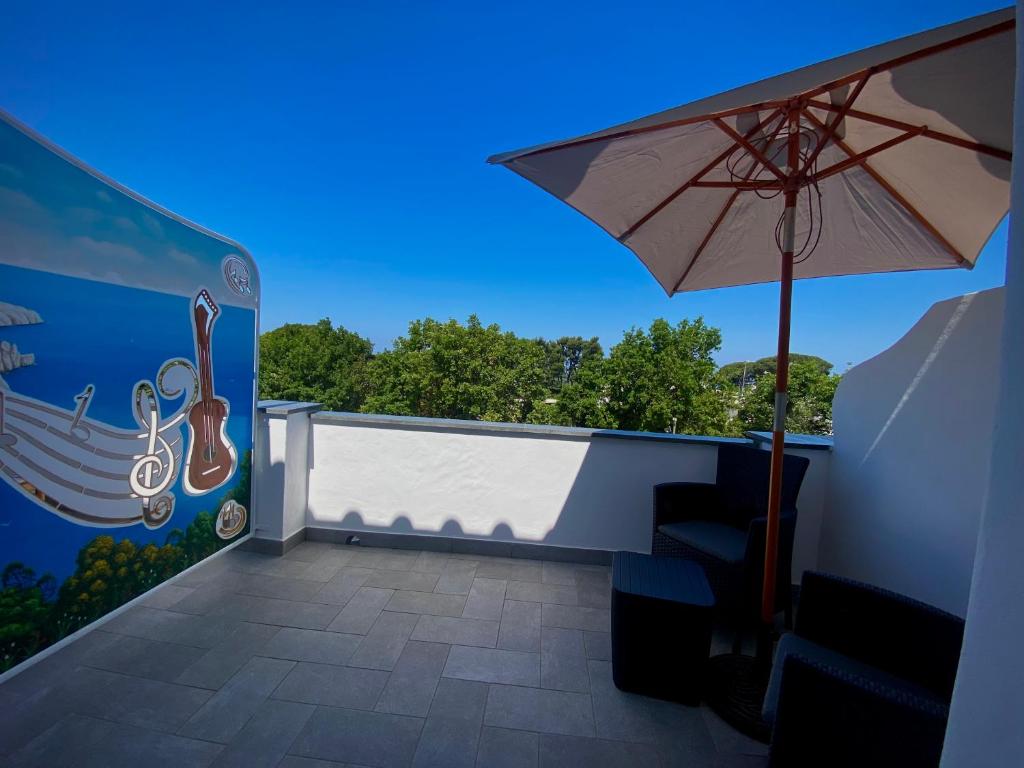 a balcony with an umbrella and a wall with a mural at Capri Melody in Anacapri