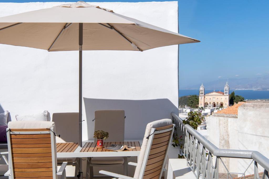 a table and chairs with an umbrella on a balcony at Rina Houses in Kampos Paros