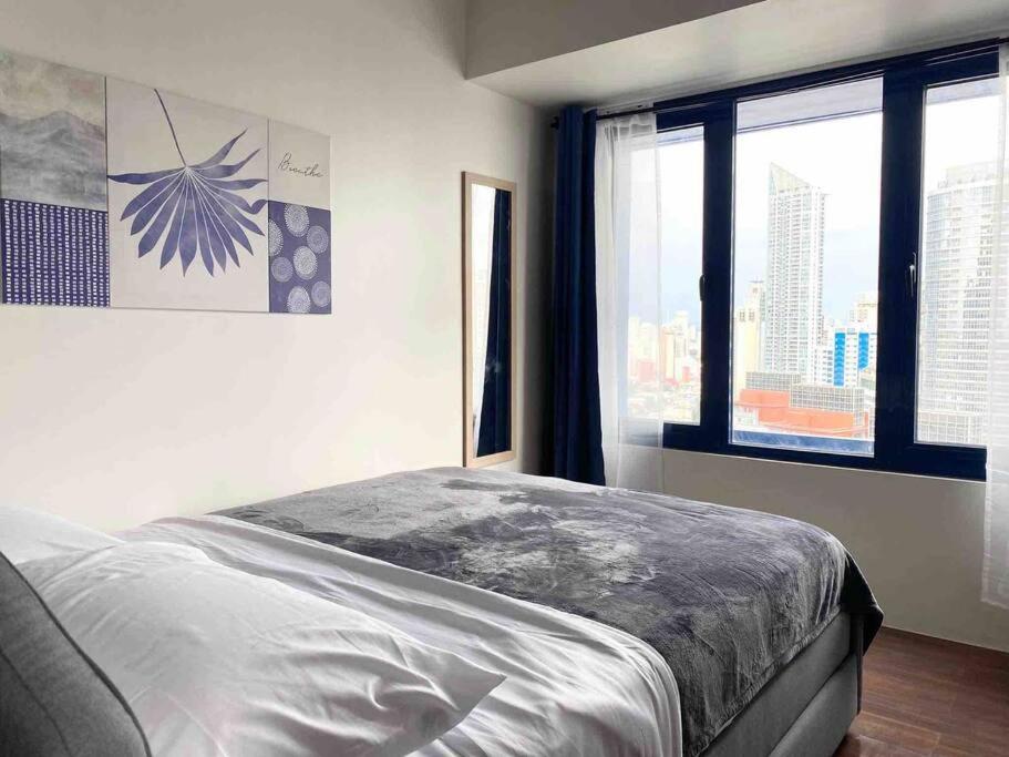 a bedroom with a bed and a large window at Air Residences Makati - fully furnished condo with skyline views! in Manila