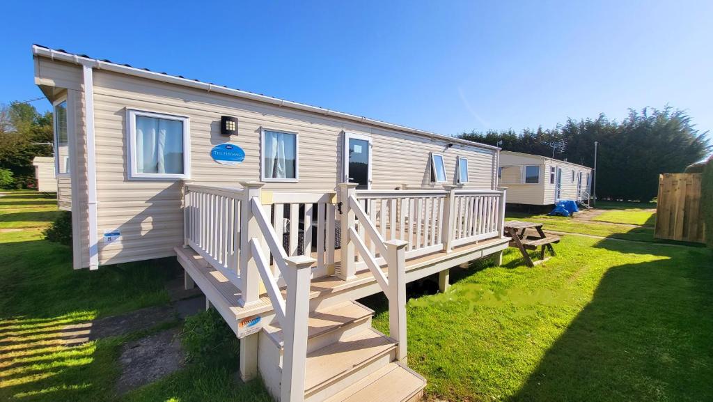 uma casa móvel com um alpendre e um deque de madeira em K & K Caravan Southview em Skegness