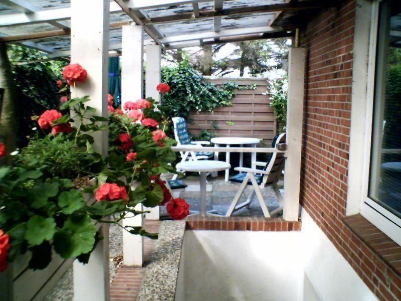 eine Terrasse mit Rosen, einem Tisch und Stühlen in der Unterkunft Haus Halliger, Appartment Ramon in Westerland