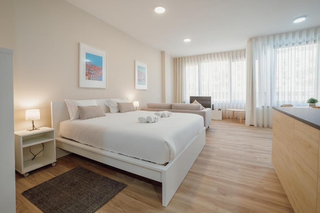 ein weißes Schlafzimmer mit einem großen Bett und einem Sofa in der Unterkunft Modern Trindade by Homing in Porto