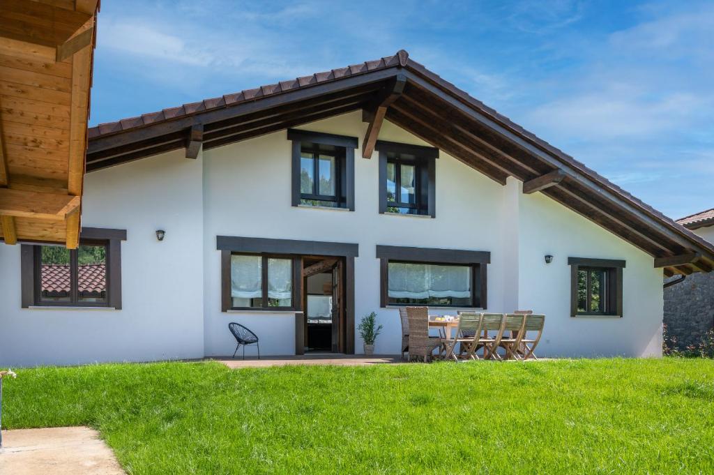 a white house with black windows and green grass at Fidalsa North Style in Arosteguieta