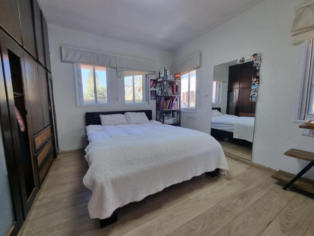 1 Schlafzimmer mit einem großen weißen Bett und 2 Fenstern in der Unterkunft shirly three bedroom house in Herzlia