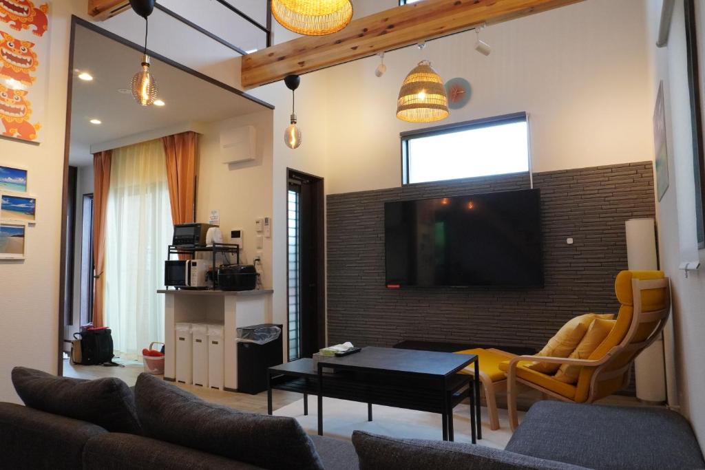 sala de estar con sofá y TV en la pared en きくのこ3缶ヴィラ＆テラス　 en Isla Miyako