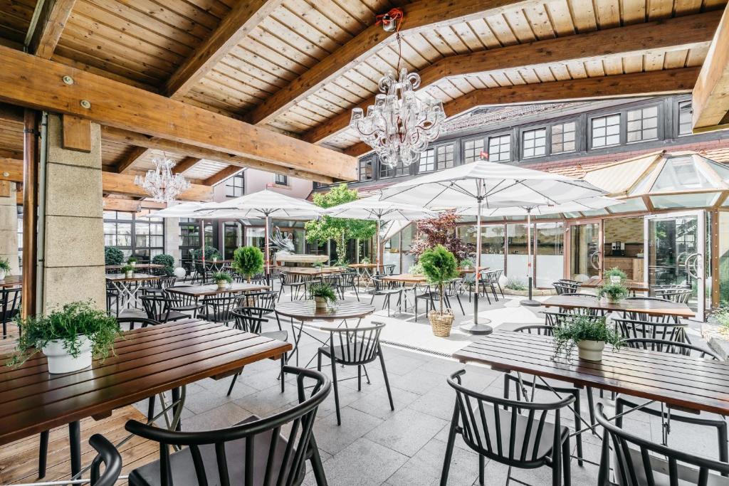 an outdoor patio with tables and chairs and umbrellas at Hotel Riesengebirge in Neuhof an der Zenn